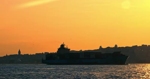 Container Ship Sailing at Colorful Sunset Near City