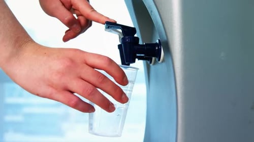 Female executive drinking water from the water purifier
