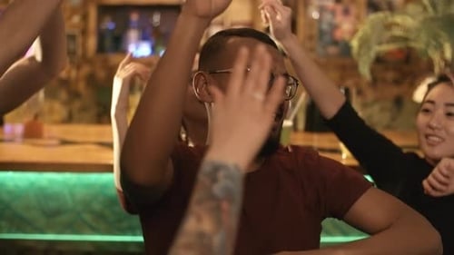 Excited Friends Dancing Together at Night in Bar