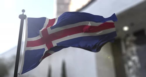 Realistic Flag of Iceland Waving on Pole with Building Background