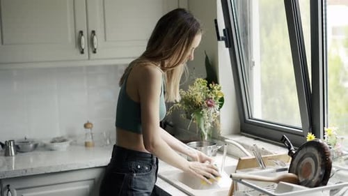 Woman Washing Dishes in a Bright Kitchen