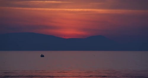 People Silhouettes On Fishing Boat In The Sea At Sunset