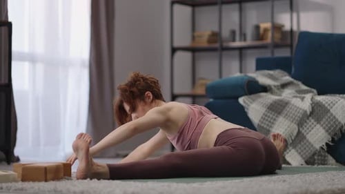 Woman Stretching Legs Seated on Yoga Mat