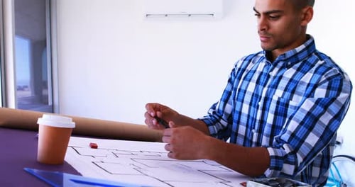 Male architect working on blueprint over drafting table 4k