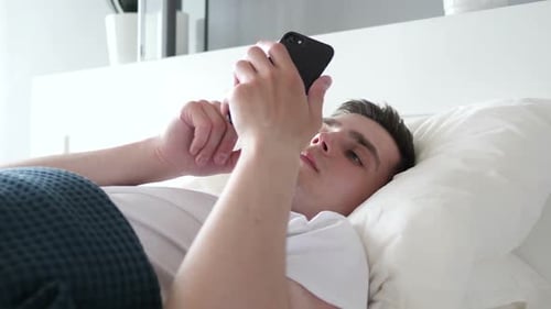 Close Up of Man Using Smartphone While Lying in Bed