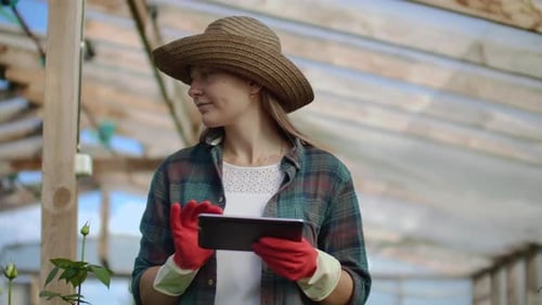 Young Woman Uses Tablet in Greenhouse