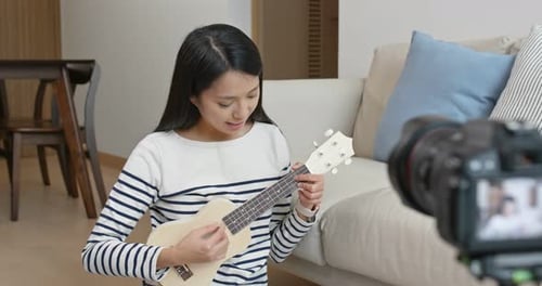 Mujer enseña el ukelele y graba Vídeo ante la cámara para las redes sociales