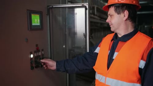Man Adjusting Control Panel Inside Factory