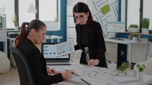 Office Workers Using Laptop and Tablet with Data Charts