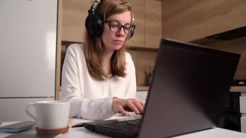 Woman Works On Laptop And Writes In Notebook