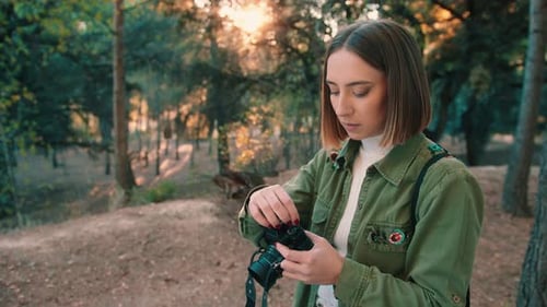 Girl rewinding analog camera film in the forest. Medium shot, fixed shot.