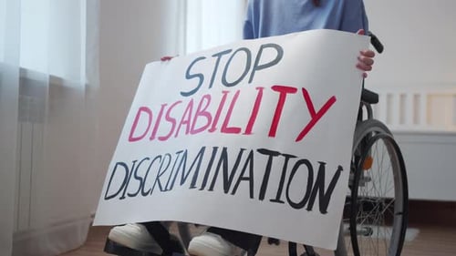 Person in Wheelchair Holding Sign Against Discrimination