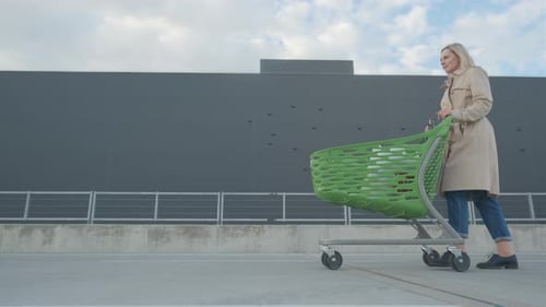 The Happy Woman Is Walking From the Supermarket with Purchases in the Cart. Shopping Concept