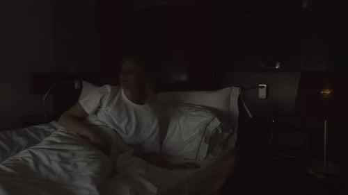 Woman Sits On Bed in Hotel Room During Day