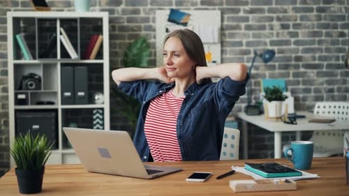 Cheerful Girl Smiling Relaxing at Work After Using Laptop Computer in Office