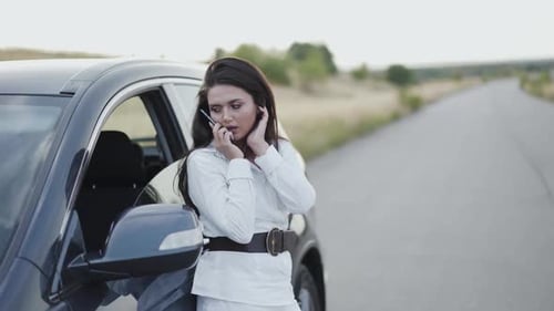 Woman Talking on Phone Next to Car on Road