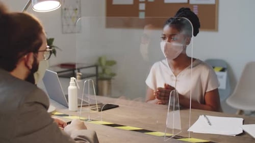 Multiethnic Male and Female Colleagues in Masks Discussing Business in Office