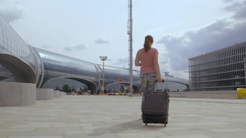 A Passenger with Suitcase Walks to Airport Building.