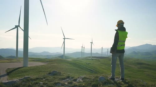 Technician Engineer in Wind Turbine Power Generator Station Standing with a Tablet in His Hands