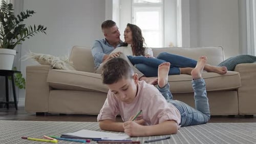 Child Draws as Parents Relax on Sofa