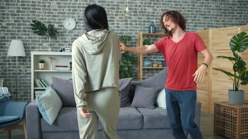Young Couple Dancing and Laughing Together in Living Room