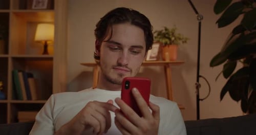Crop View of Handsome Man Using Smartphone While Sitting on Sofa at Home