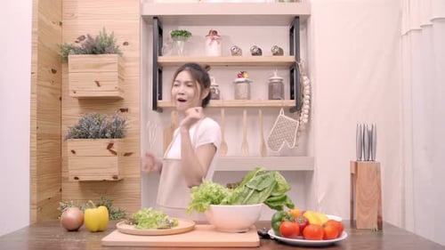 Cheerful Woman Dancing in Kitchen with Fresh Vegetables