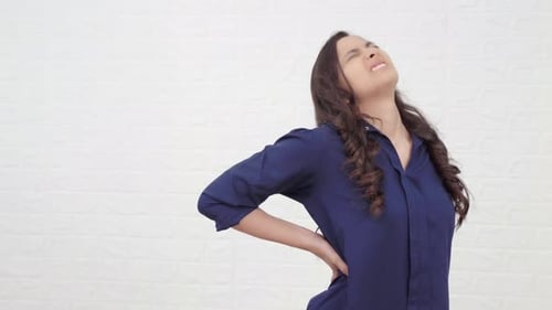 Woman Experiencing Lower Back Pain in Blue Shirt
