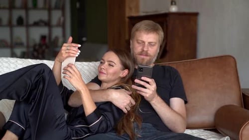 Relaxing Couple Using Mobile Phones on Couch
