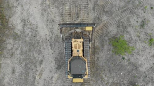 Top Aerial View on Tracked Bulldozer Rides on Sandy Road at Construction Site