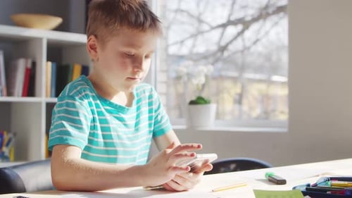 Boy is Doing Homework at the Table. Cute Child is Learning at Home.