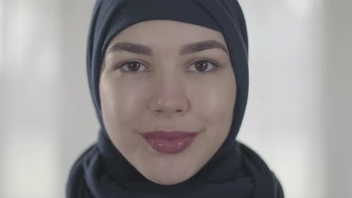 Porträt einer jungen lächelnden Ostfrau in moderner muslimischer Kleidung und wunderschönem schwarzen Kopfschmuck