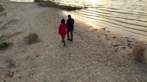 Couple Walking By The Lake At Sunset On Aerial View