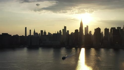 A dolly shoting forward towards New York City & a golden sunset, looking down at the river as a ferr
