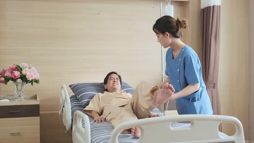 Asian female Physiotherapist working with patient in clinic doing leg stretching exercises