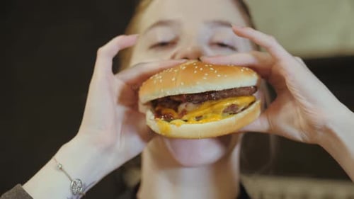 Young Adult Woman Eating Delicious Burger Close Up