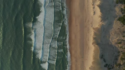 Beach with Blue Ocean Waves Crashing Against Shore Line, Aerial Birds Eye Top Shot, Slow Forward