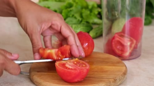 Cutting a Ripe Red Tomato on Cutting Board
