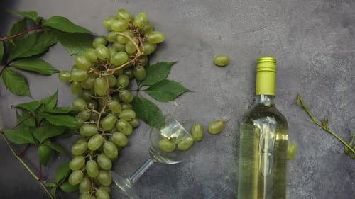 Top View of Bottle White Wine Green Vine Wineglass and Ripe Grape on Vintage Gray Stone Table