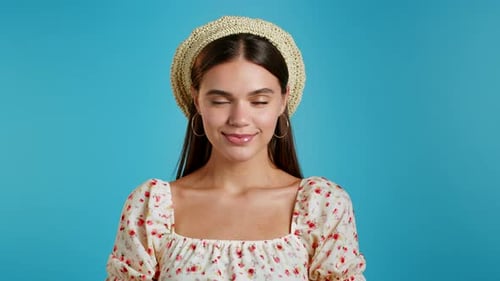 Young Woman in Floral Dress and Beret Looking To Camera. Portrait of Flirting Beautiful Girl on Blue