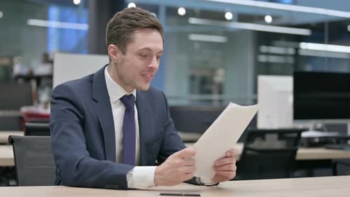 Businessman Upset While Reading Documents in Office