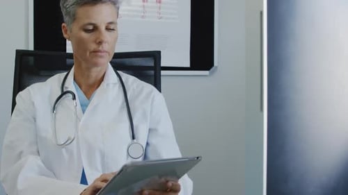 Doctor Uses Tablet and Smiles in Hospital Office