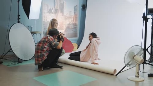Fotógrafo tomando fotos de una modelo negra, maquilladora en un momento aplicándose maquillaje en Pretty