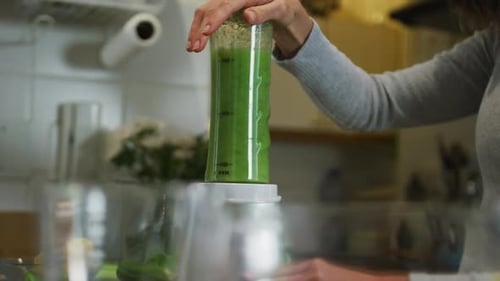 Kaukasische Frau bereitet grünen Gemüse-Smoothie in der Küche zu