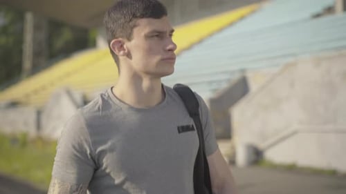 Serious Caucasian Sportsman Walking on Stadium. Portrait of Confident Handsome Man Checking Time on