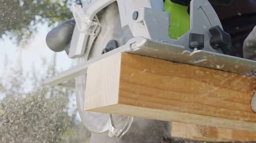 Slow motion of a round saw cutting through wood with dust flying