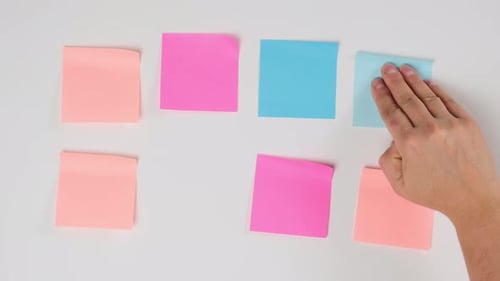 female hand gluing blank square multicolored stickers on white board, business concept