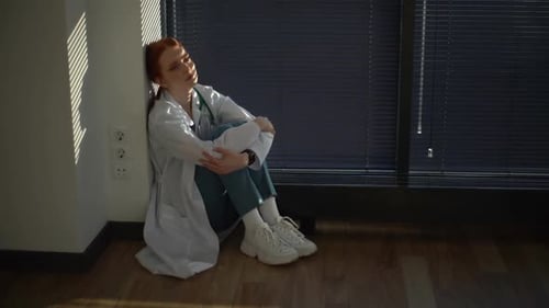 Overworked Doctor Sitting on Hospital Floor
