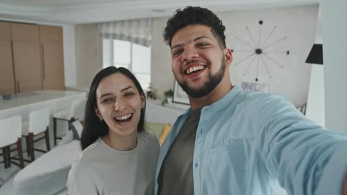 Happy Couple Waving From Modern Apartment