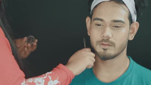 Close up of professional make up artist fixing mans beard and doing the make up